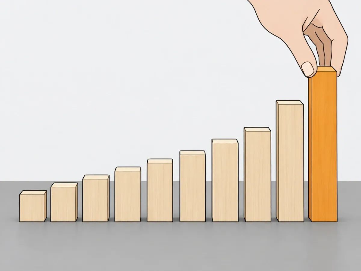 A hand placing the tallest of ten wooden blocks at the end of a row that rises in steps