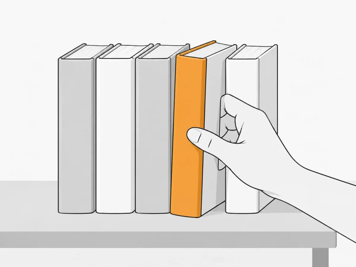 A hand pulling one book from a row of five on a table