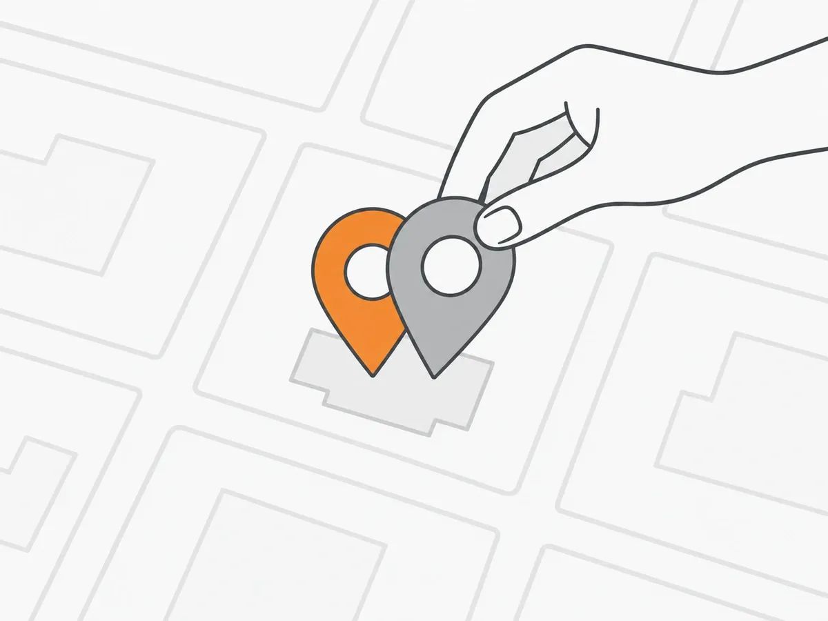 A hand sliding a grey map pin onto an orange map pin that stands on the same building on a street map