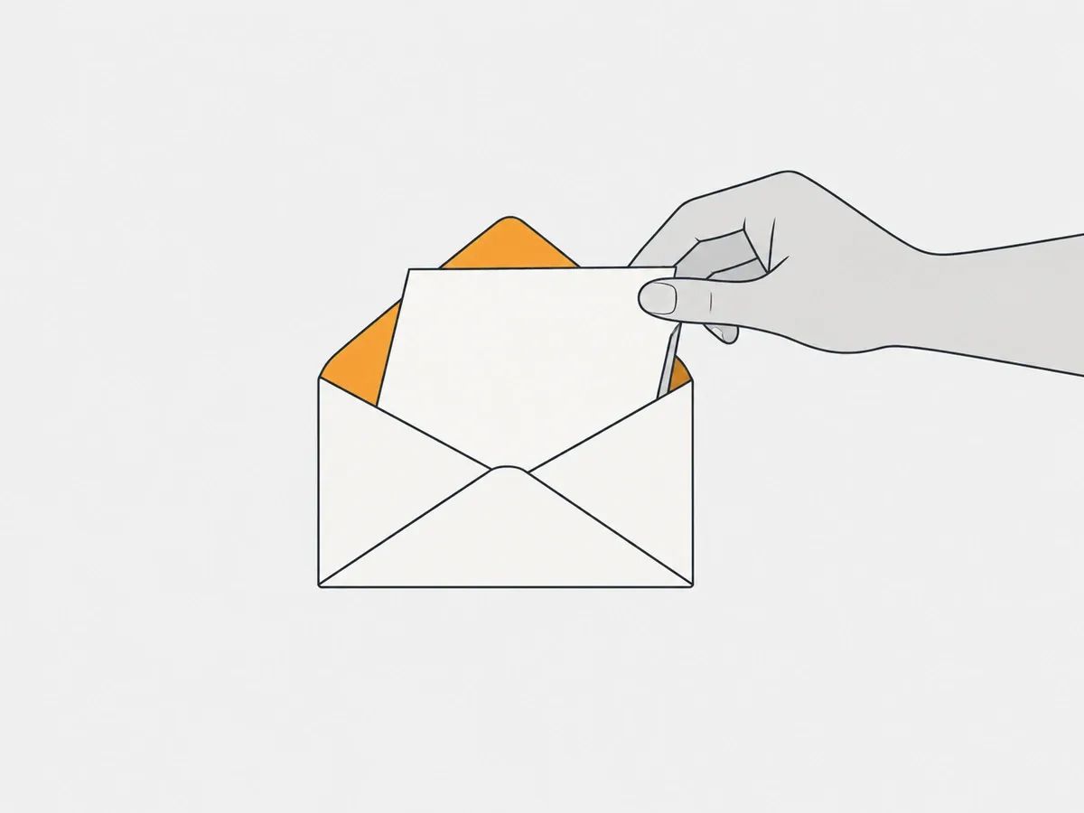 A hand sliding a blank card into an open envelope