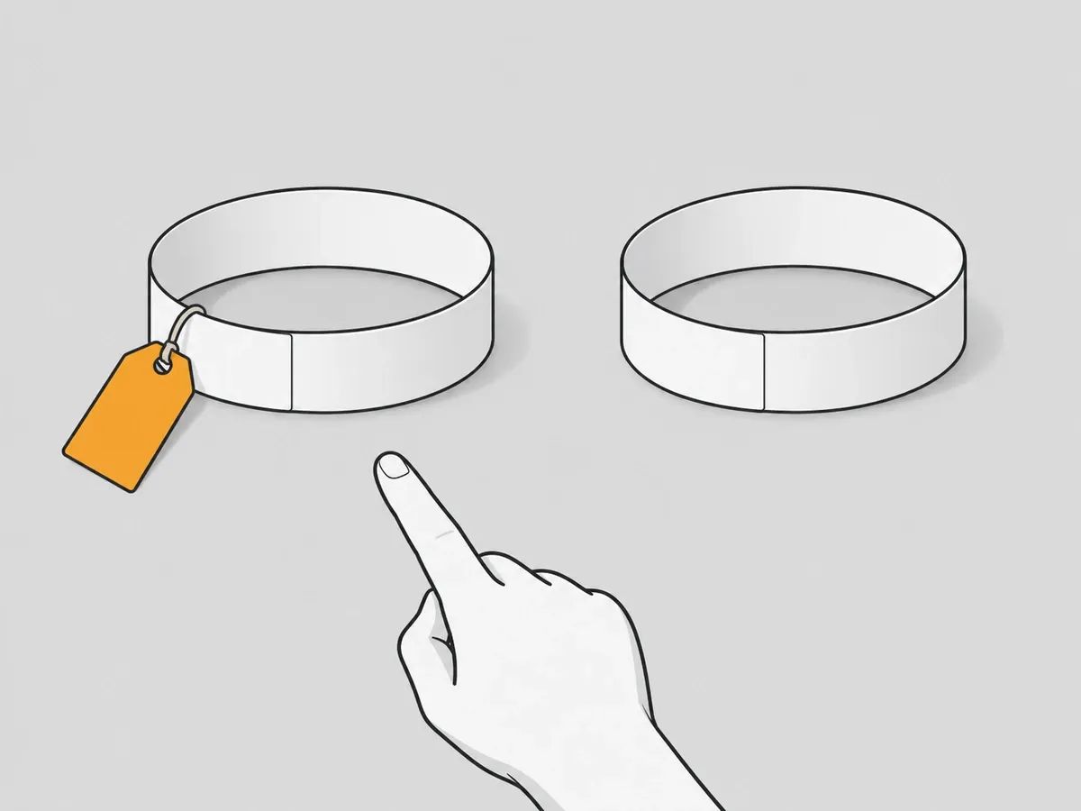 Two paper chain loops side by side, one with a small orange tag tied to it and one without, with a hand pointing at the tagged one